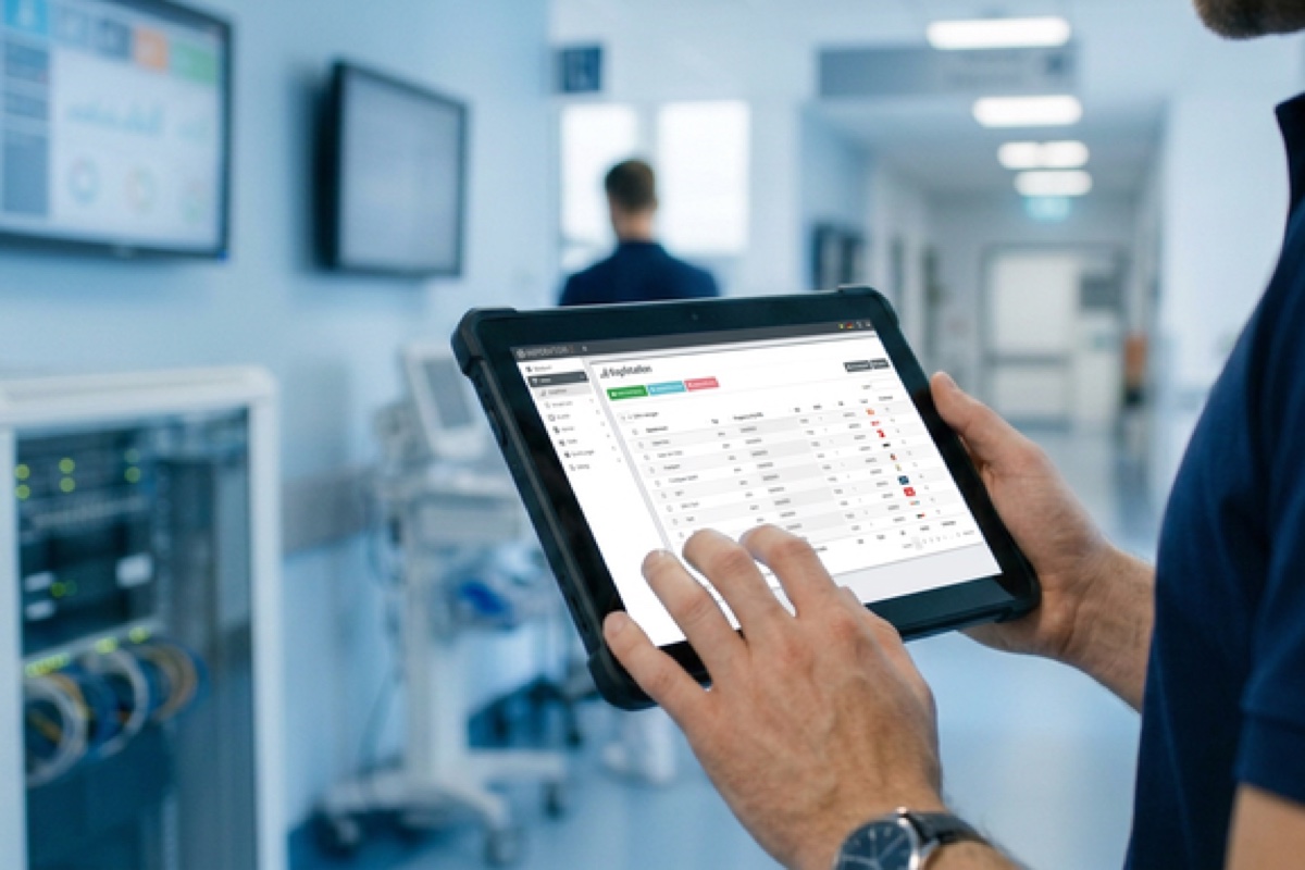 Techniker mit Tablet vor dem Netzwerkschrank im Klinikflur