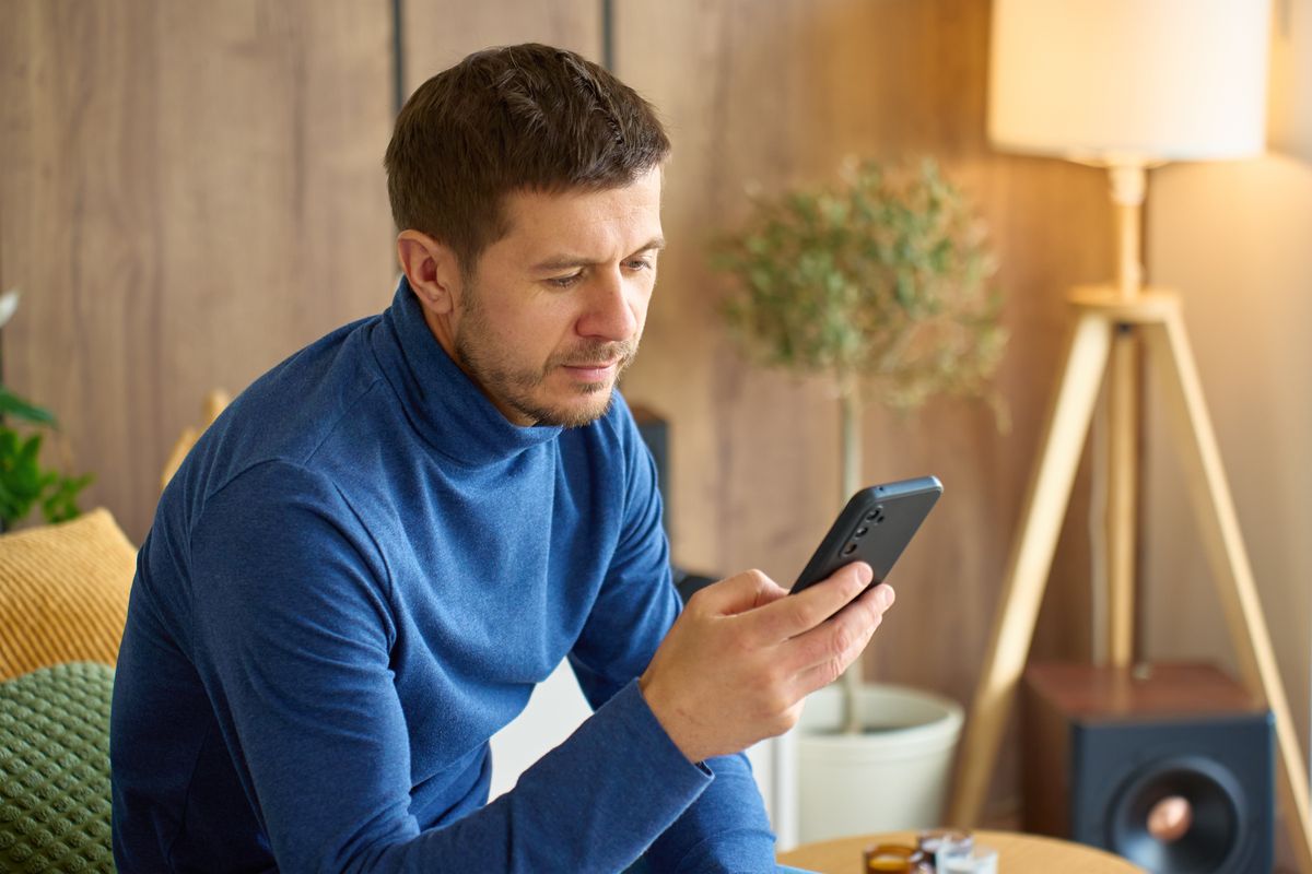 Mann mit Smartphone zu Hause, vor der Reha informiert